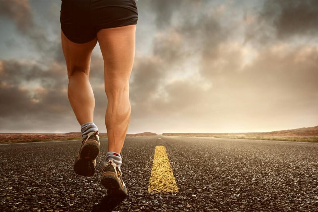 Runner's legs on a road during a sunset, symbolizing endurance and outdoor fitness training.